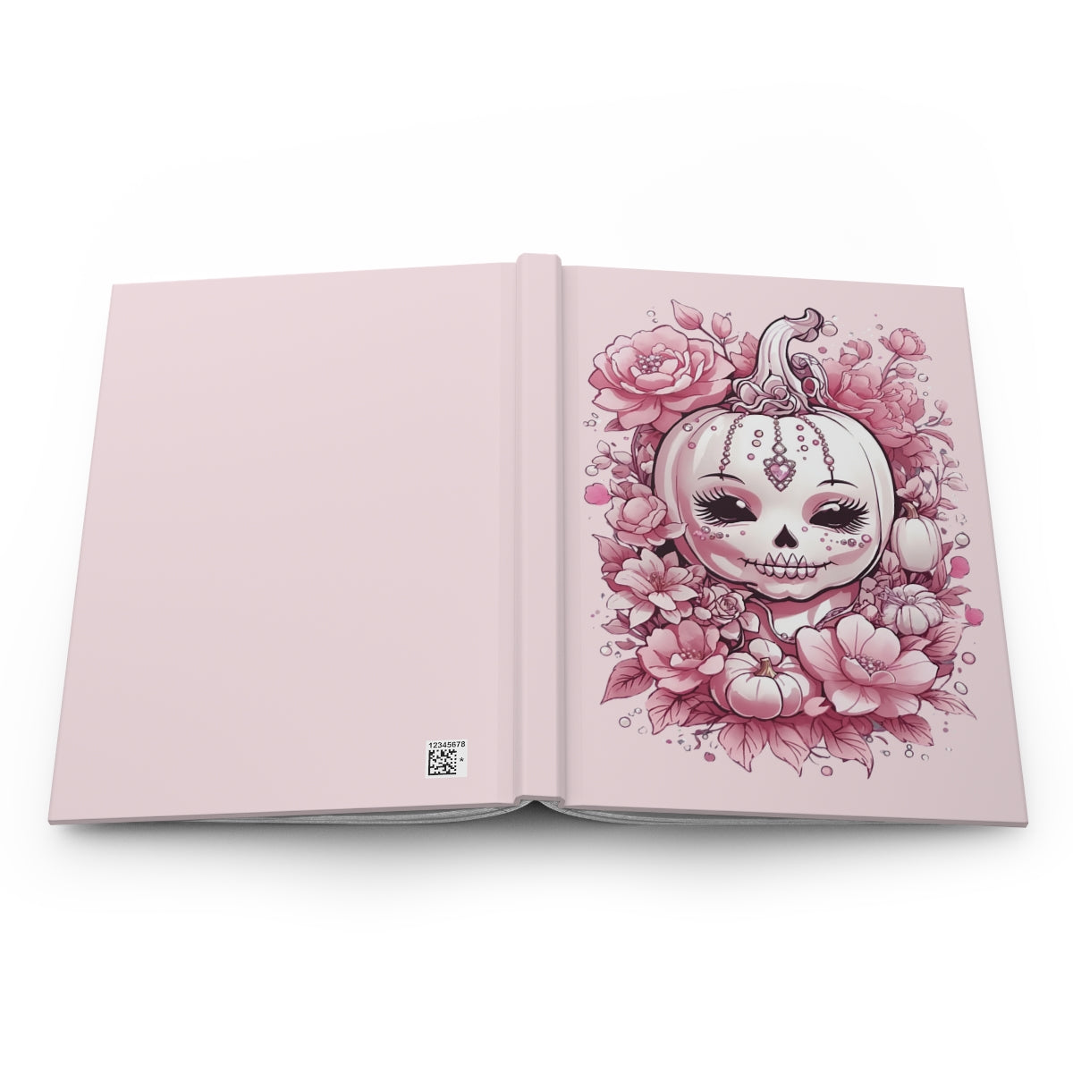 Open hardcover notebook with a pink halloween pumpkin and surrounded by flowers and jewelry on a pastel pink background