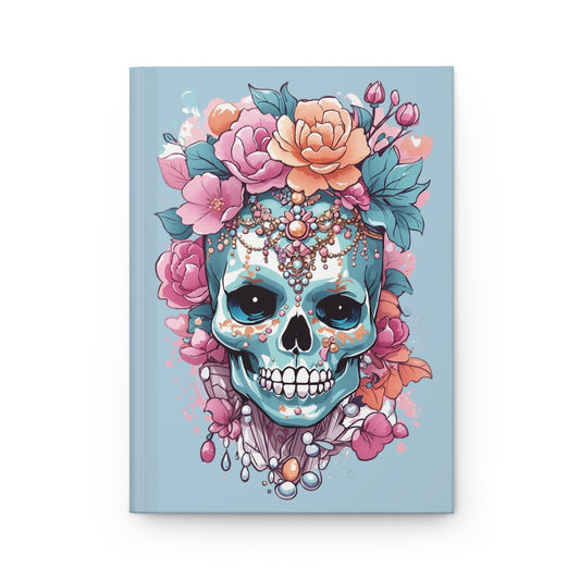Pastel blue journal cover with an illustration of a pastel colored skull accessorized fashionably with pink flowers and jewelry