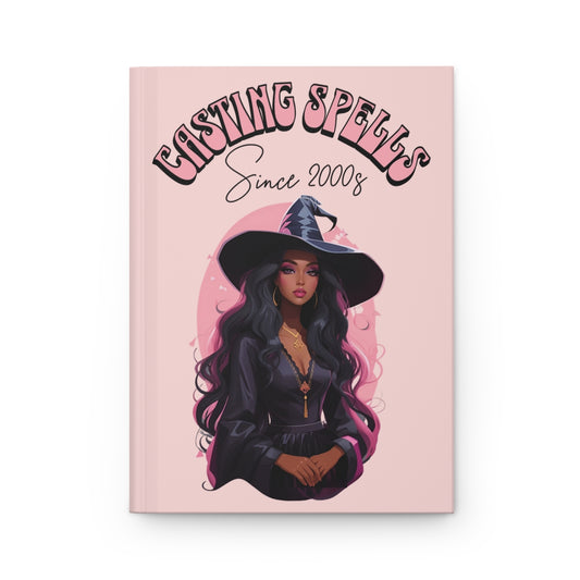 Magical-themed pastel pink hardcover journal with a beautiful black witch and text 'Casting Spells Since 2000s' written in pink retro groovy letters 