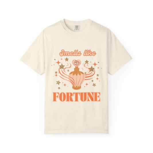 Beige t-shirt with orange graphic of a perfume bottle with stars and text 'Smells like Fortune' on a white background