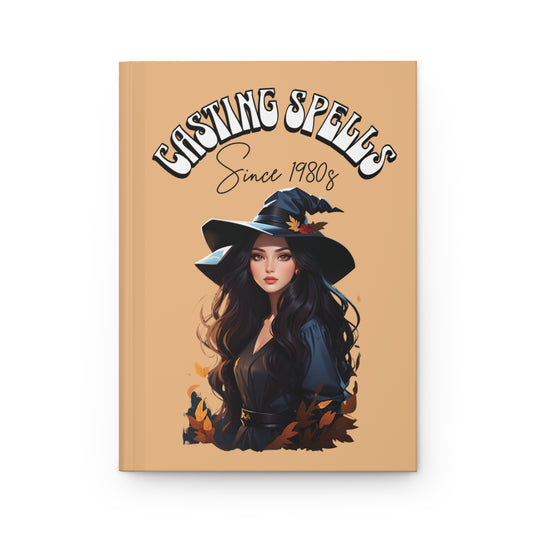 Notebook cover with a beautiful witch girl illustration, fall leaves and 'Casting Spells Since 1980s' text written in retro groovy aesthetic letters on a beige background